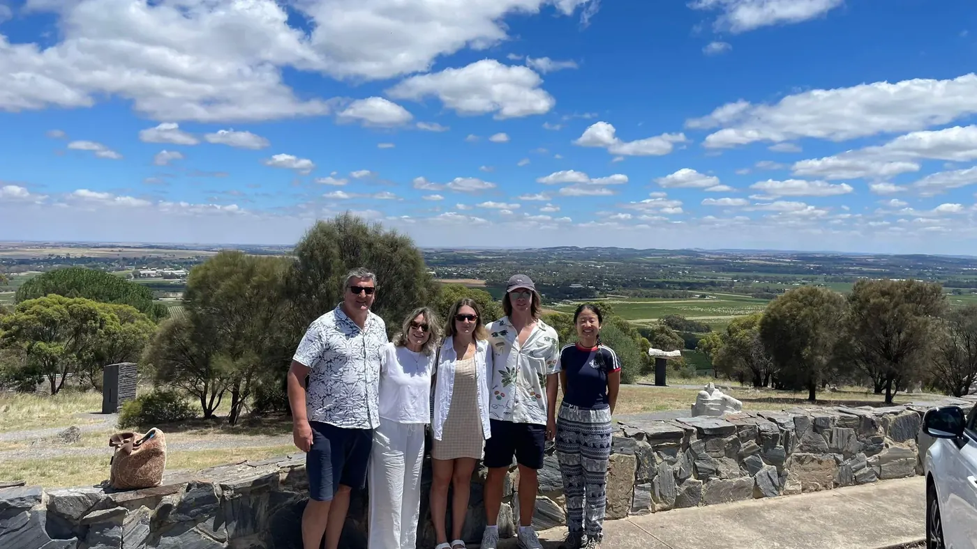 Tour group at a Barossa lookout with vineyards and rolling farmland behind them