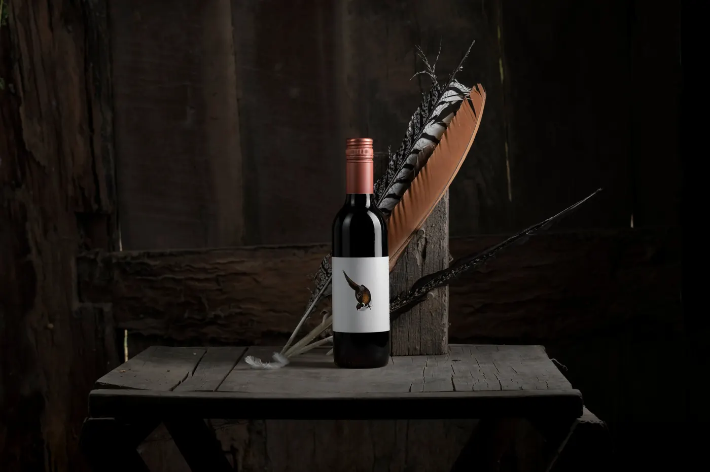 A bottle of Pheasant Farm red with a pheasant feather on a dark timber block