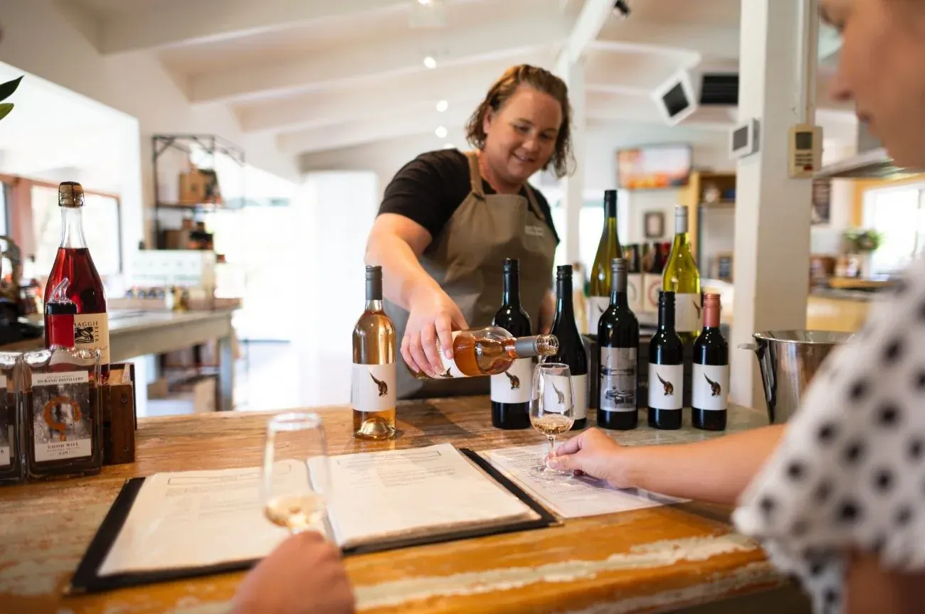 Farm Shop host pouring a Pheasant Farm wine across the tasting counter