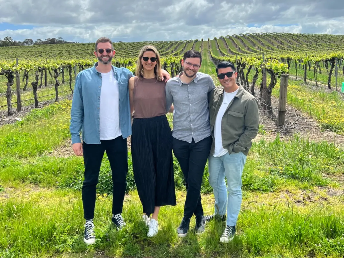 Four guests standing between spring vine rows on a Barossa estate