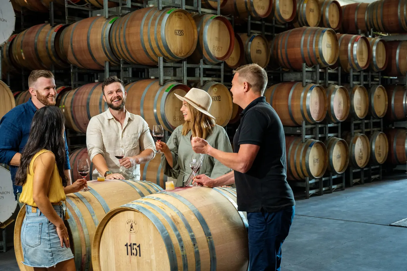 Guests tasting among stacked oak barrels in a working Barossa barrel hall