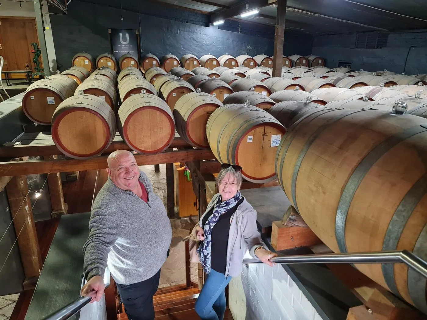 Guests on the stairs of a barrel hall stacked with oak casks