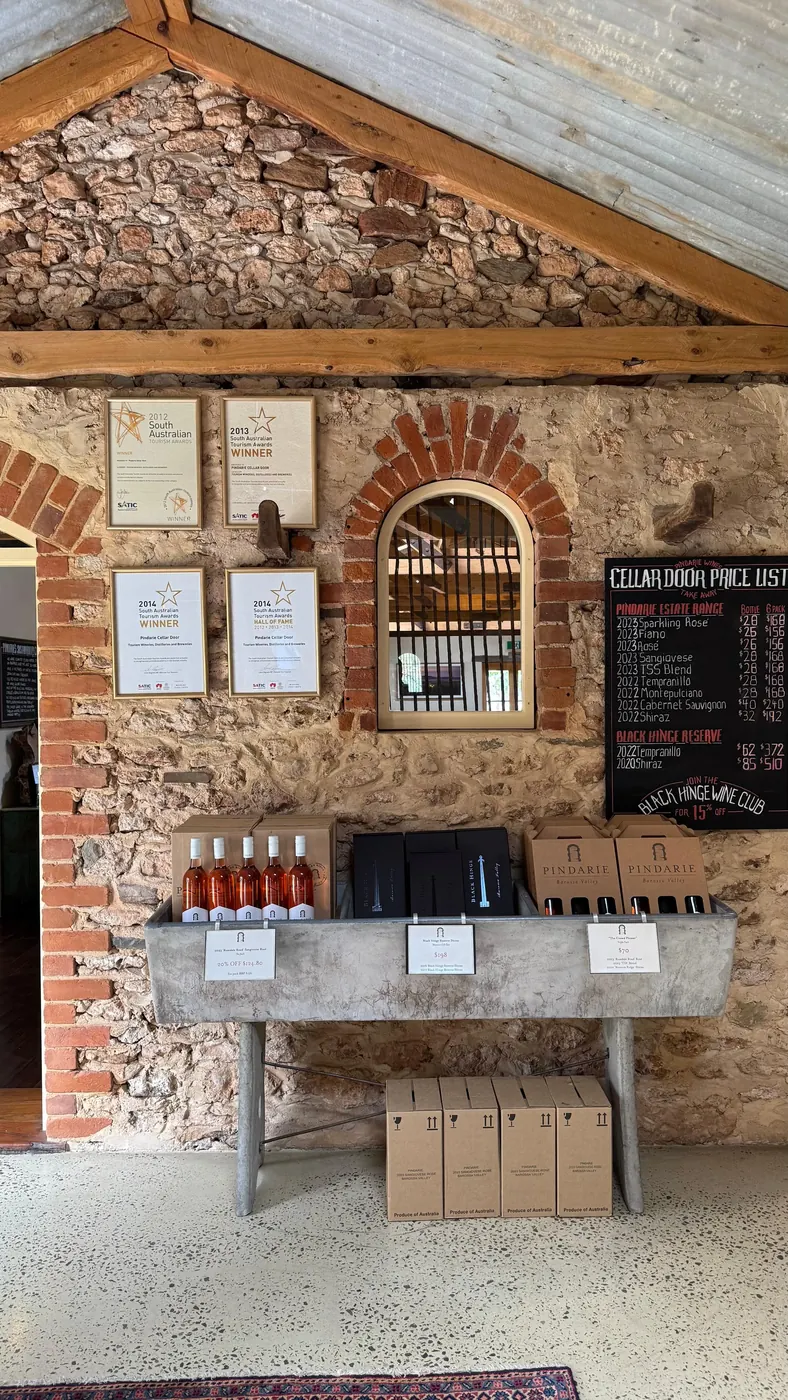Cellar-door price list and trophy certificates above a row of bottles at a Barossa estate